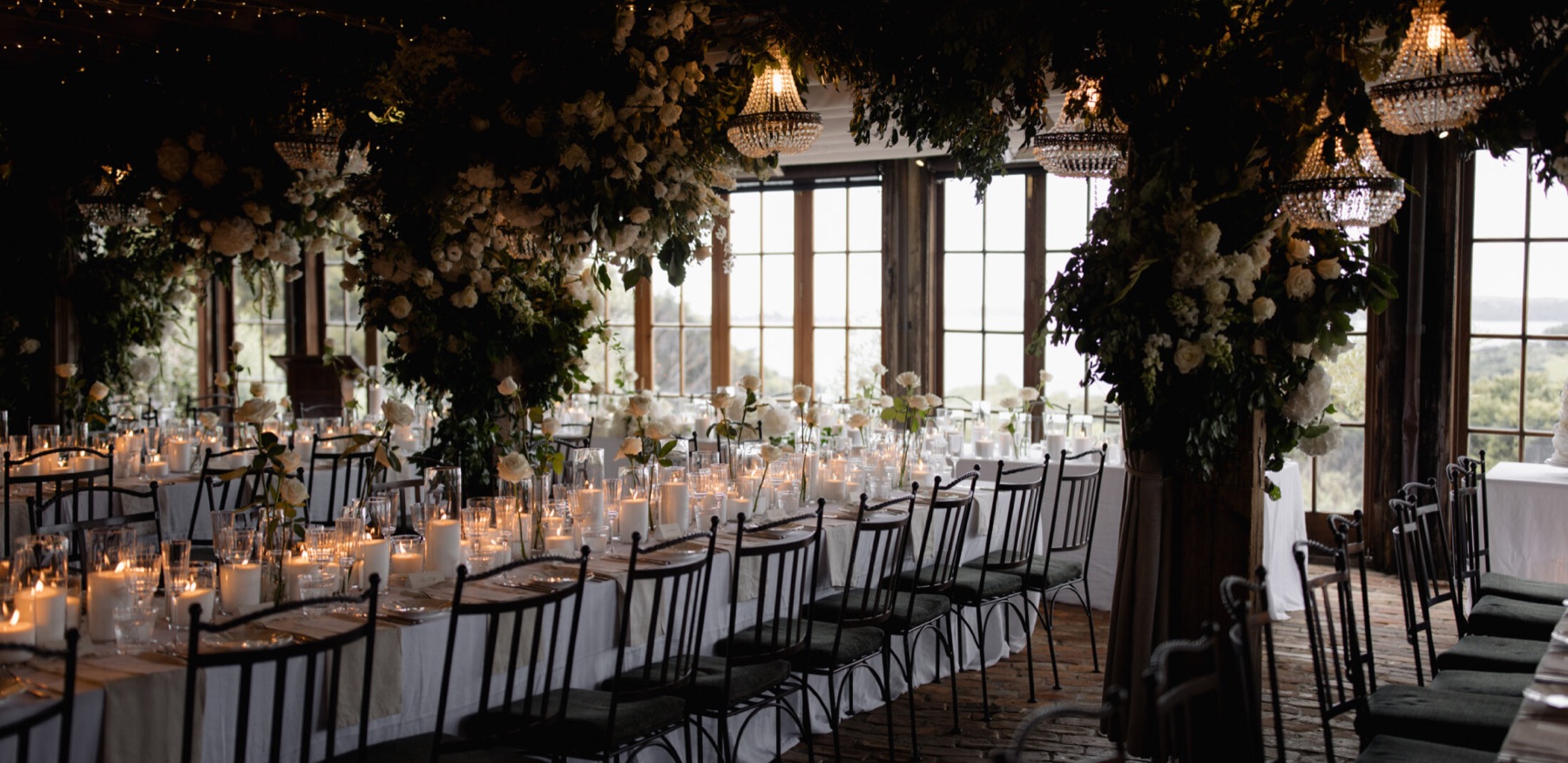 A candlelit wedding reception hall dressed with flowers